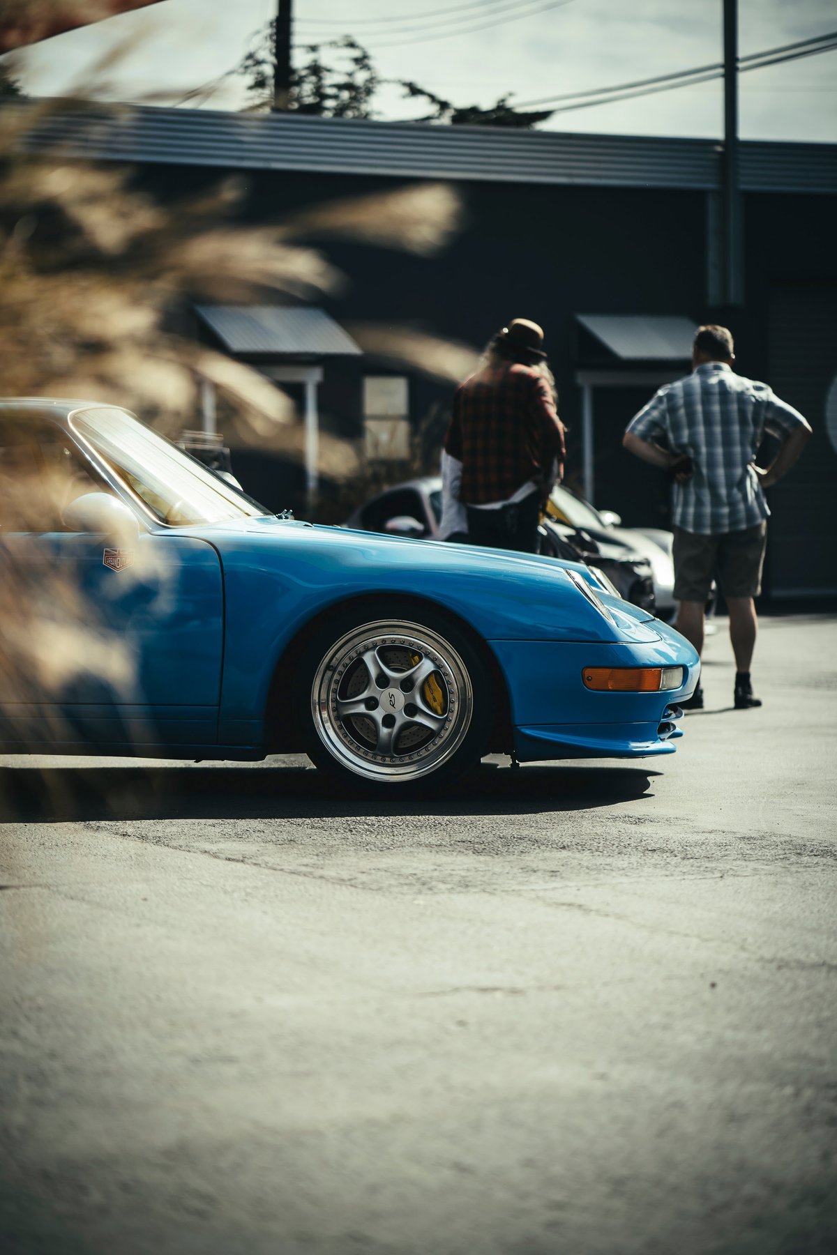 Vibrant blue Porsche 911 (964) front. Polished multi-spoke rims, yellow calipers, and integrated bumper detail.