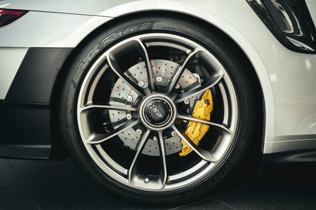 White Porsche 911 GT3 RS rear multi-spoke rims, yellow PCCB calipers, drilled rotors, and black lower trim.