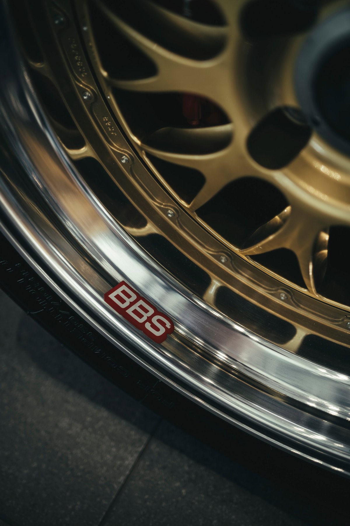 Close-up of a gold BBS multi-spoke wheel with a polished lip, showcasing red brake calipers. Premium aftermarket rim.