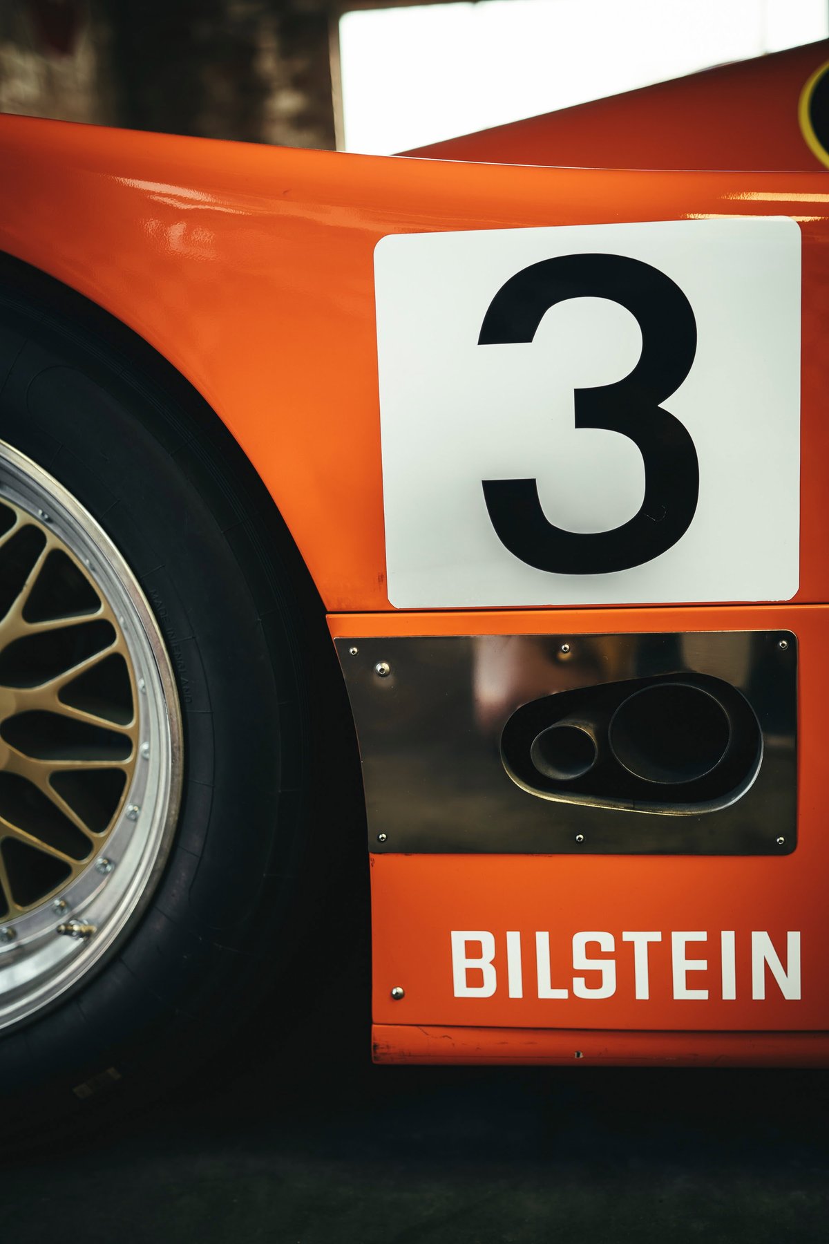 Orange Porsche 917 race car side, #3, gold BBS-style rims, dual side exhaust, and Bilstein livery detail.