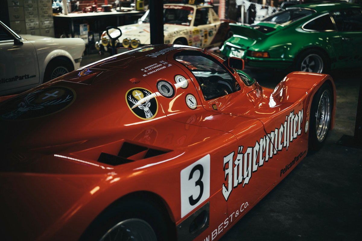 Porsche 962C Group C prototype race car in iconic Jägermeister livery with #3, showing detailed vents & racing rims.