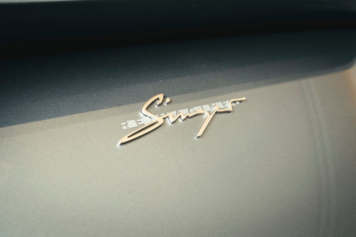 Silver Singer REIMAGINE badge on a metallic grey bespoke Porsche 911, highlighting custom trim.