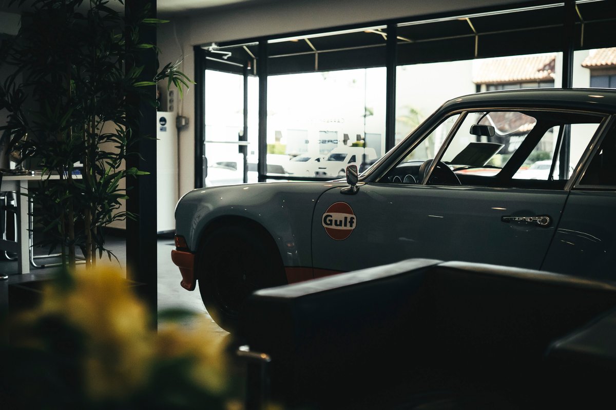 Classic Porsche 911 coupe in iconic Gulf livery: light blue body, orange lower trim, and Gulf fender badge.