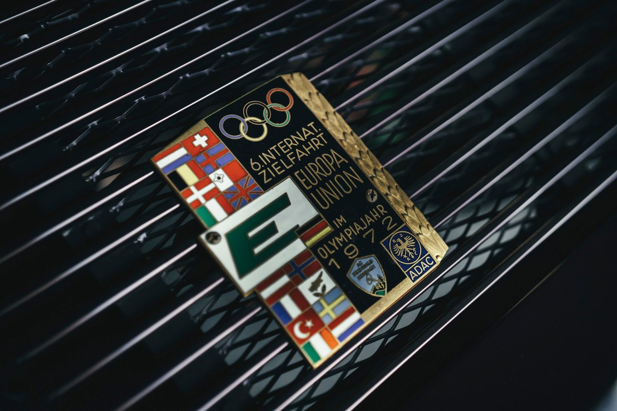Vintage 1972 Europa Union Olympic rally plaque on a classic black Porsche 911 engine lid grille.
