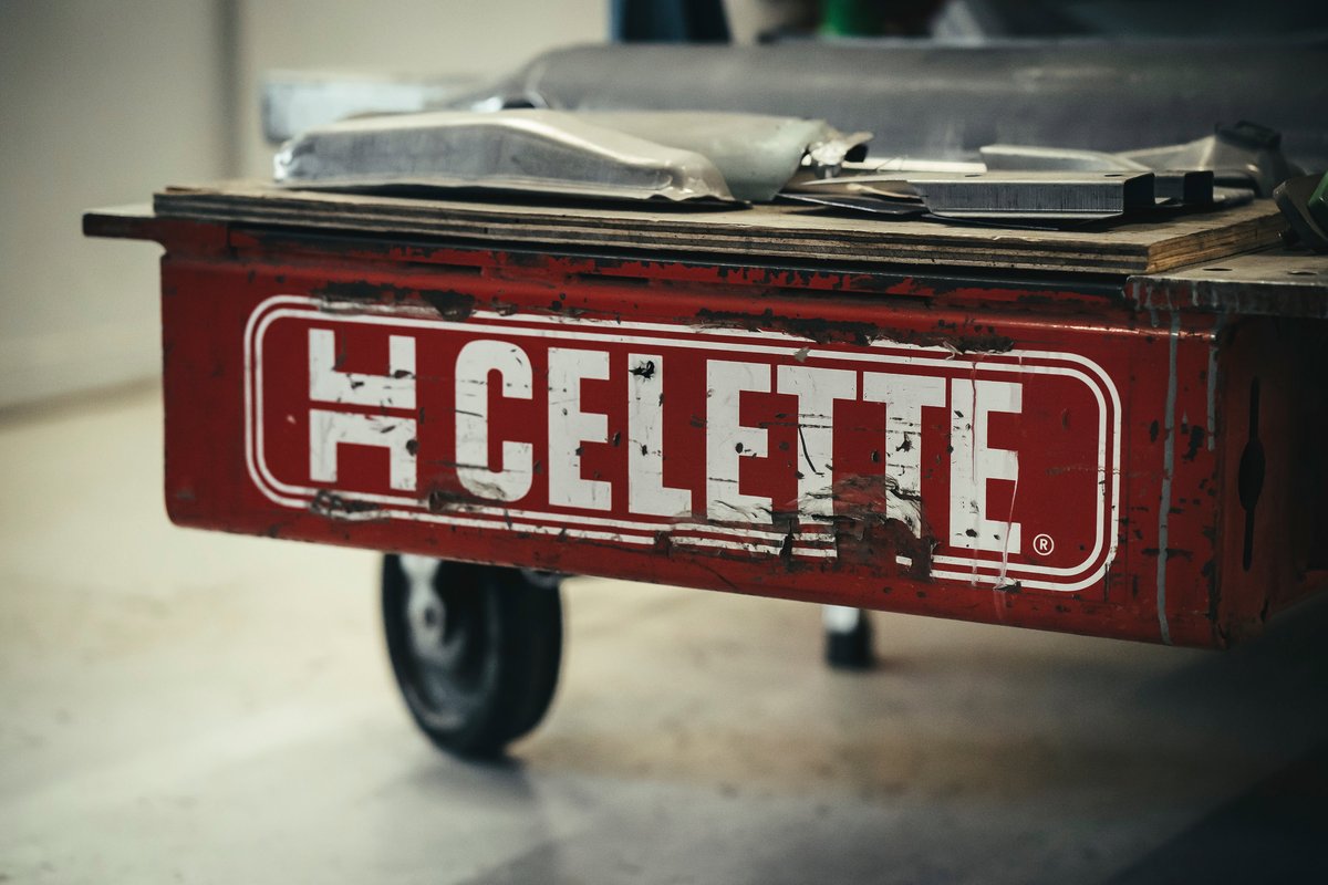 Distressed red H Celette automotive frame repair equipment with white logo, displaying restoration parts at a Los Angeles car show.