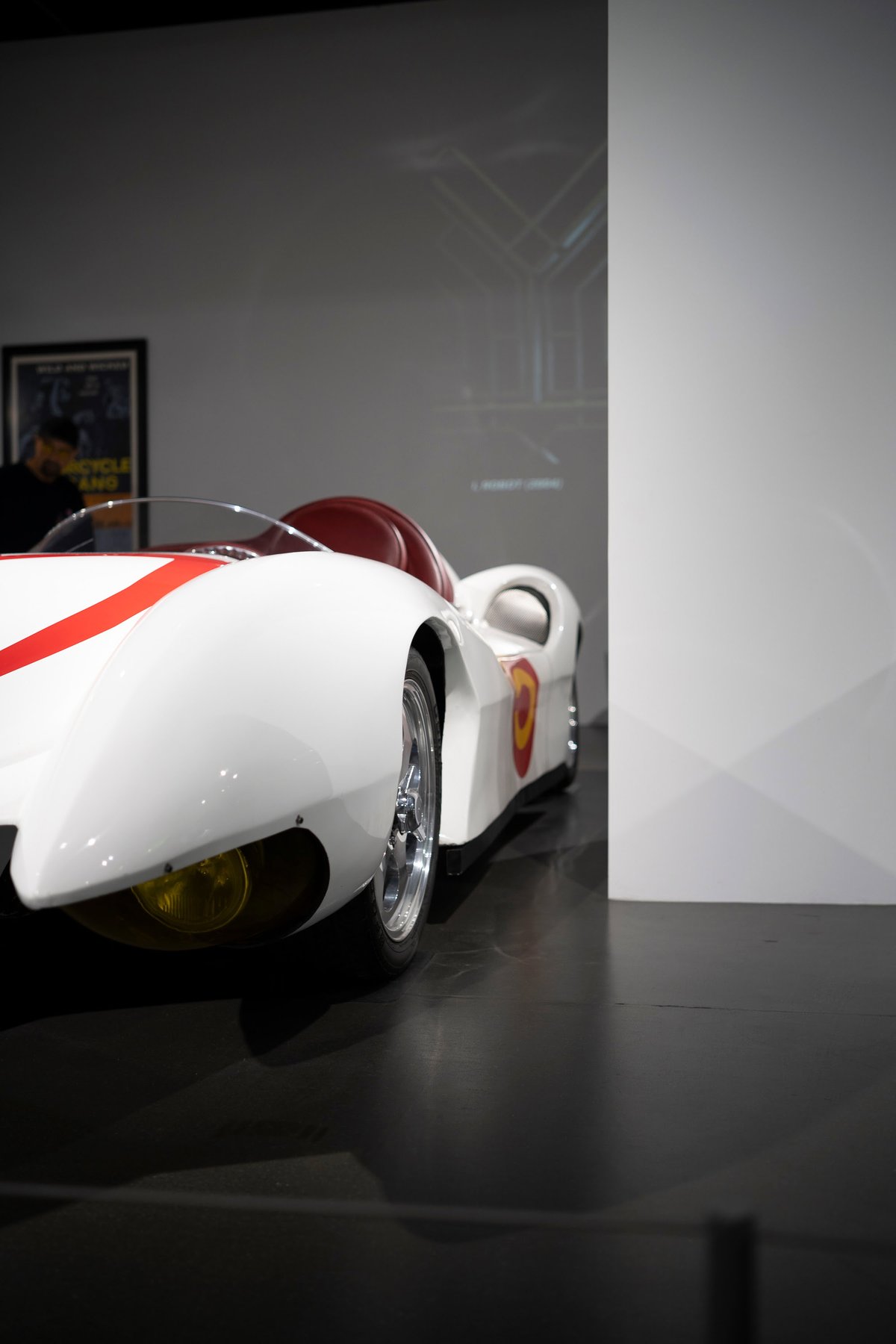White Speed Racer Mach Five replica car with red racing stripe livery, chrome multi-spoke rims, and red cockpit interior.