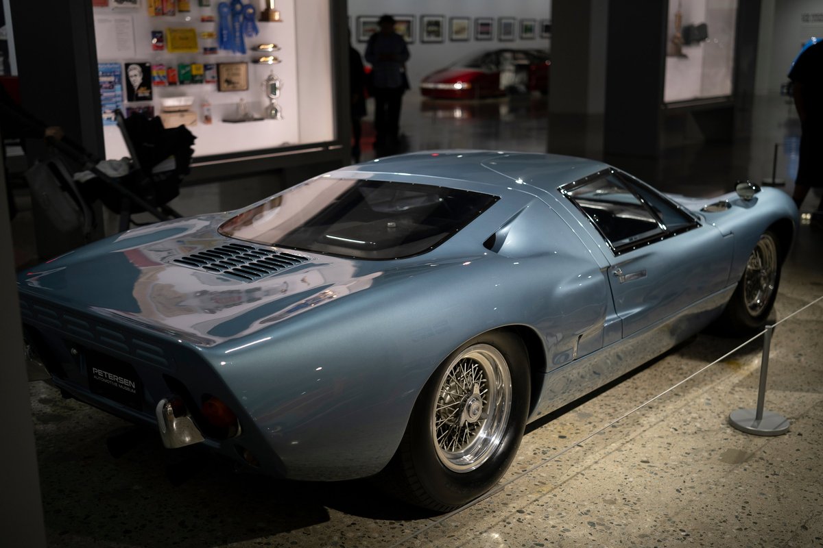 Iconic light blue metallic Ford GT40 race car, showcasing intricate wire rims & rear deck louvers at Petersen Museum.