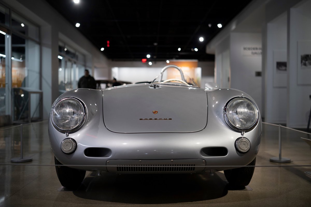 Classic silver Porsche 550 Spyder front, displaying its iconic round headlamps, low grille, and distinctive Porsche hood script.
