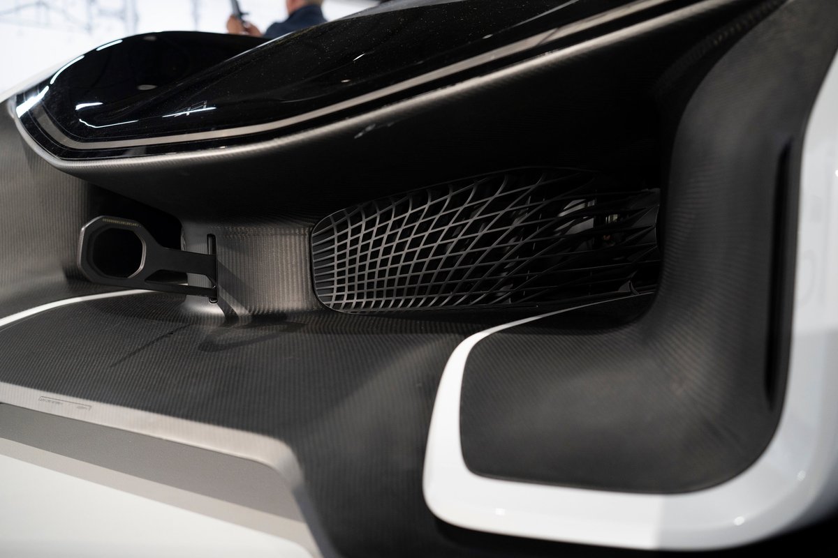 Rear view of a white & black supercar, featuring a single exhaust, intricate mesh vent, and carbon fiber rear diffuser.