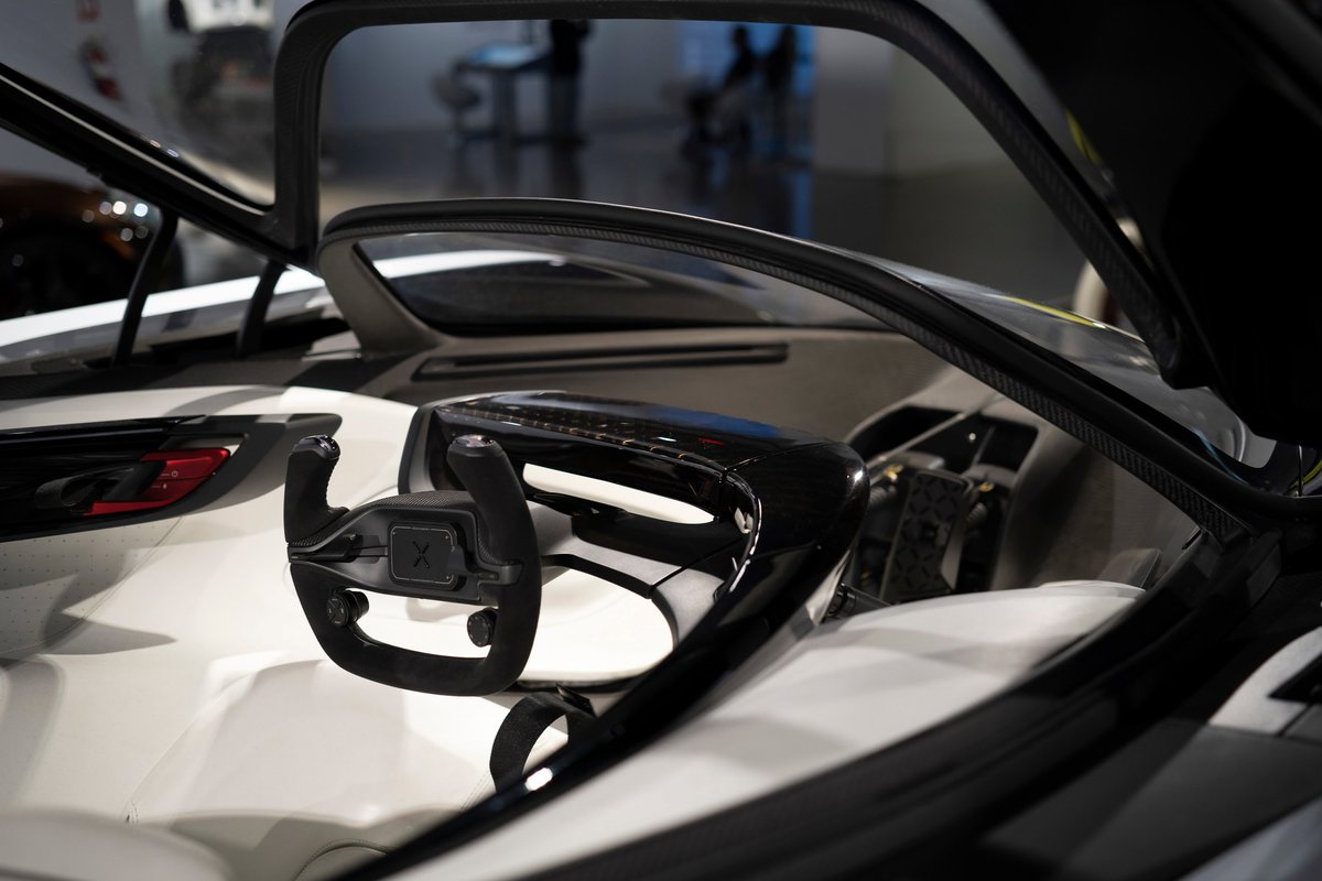 Czinger 21C hypercar cockpit view: distinct yoke steering wheel, white interior trim, and exposed carbon fiber structure.
