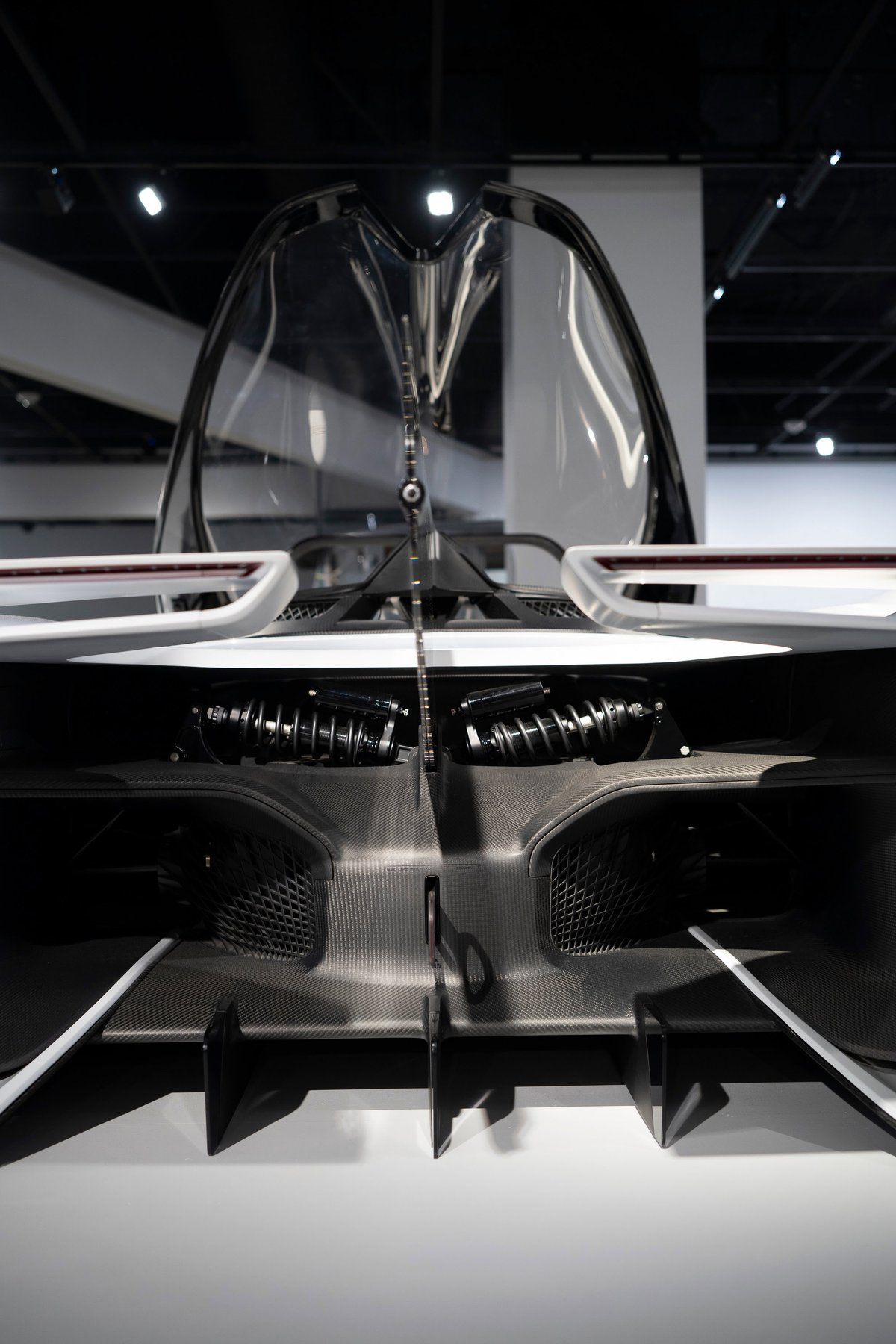 White Aston Martin Valkyrie hypercar, rear view. Exposed suspension, aggressive carbon fiber diffuser, and clear cockpit canopy detail.