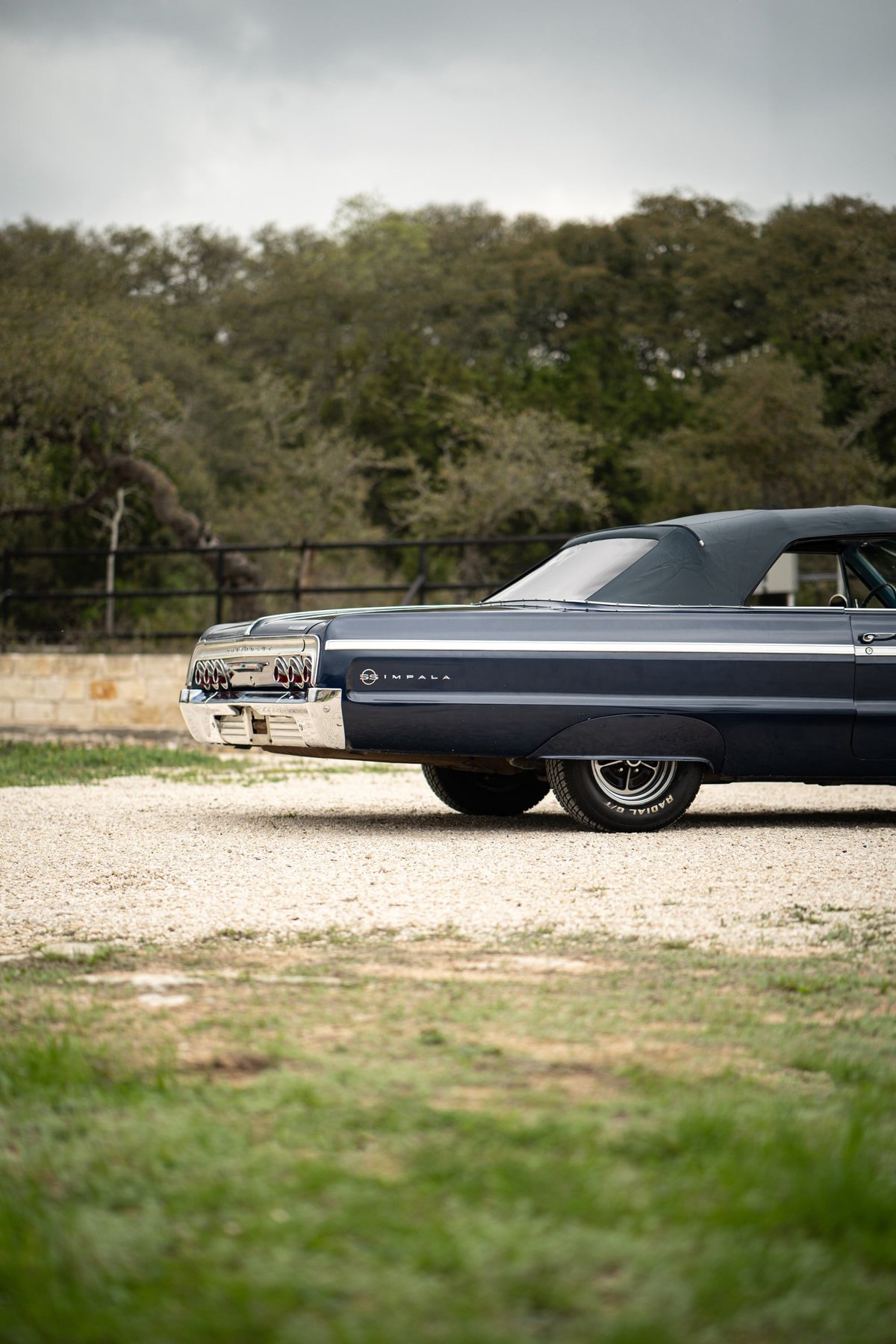 Dark blue 1964 Chevrolet Impala SS convertible rear quarter with chrome trim and rally wheels.