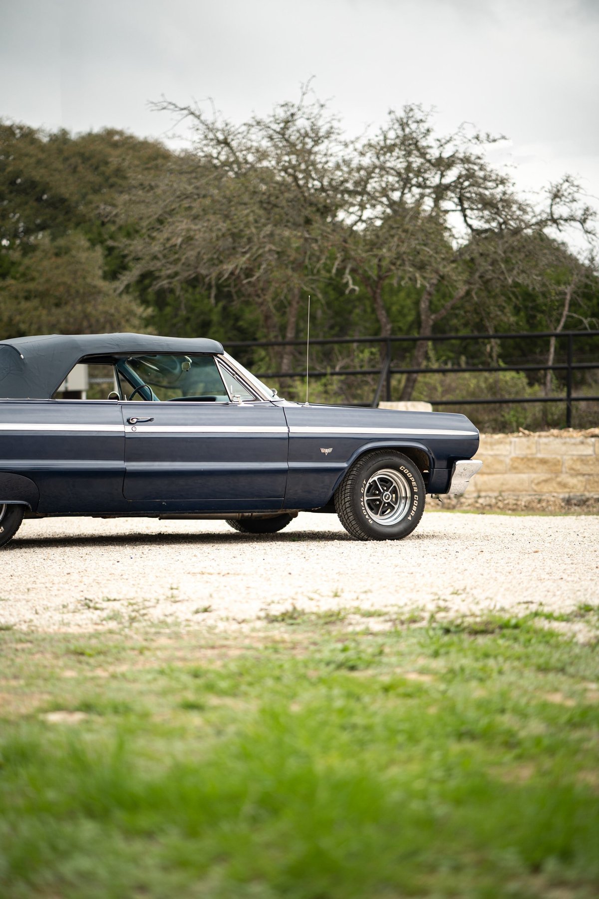 A navy blue 1964 Chevrolet Impala SS convertible with chrome trim and classic rims.