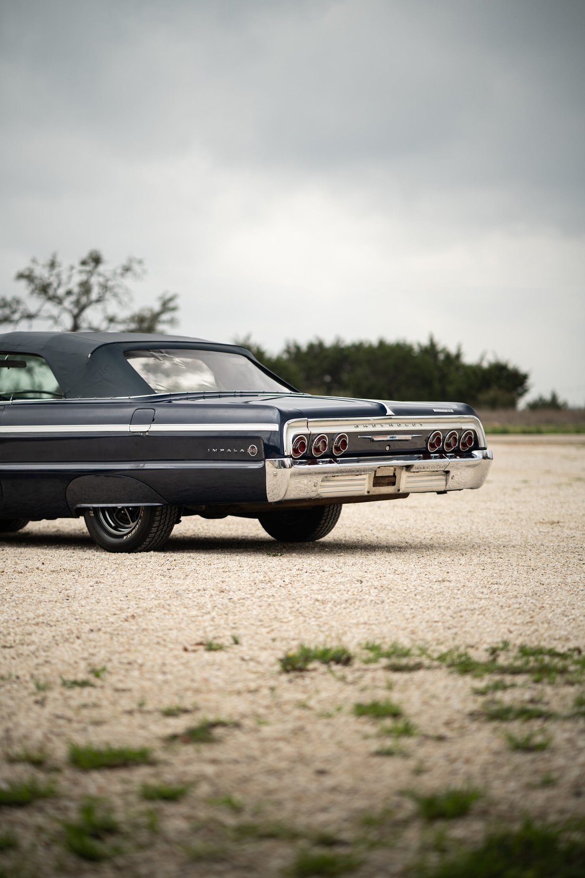 1964 Chevrolet Impala SS convertible in navy blue. Rear view showing chrome bumper & triple tail lights.
