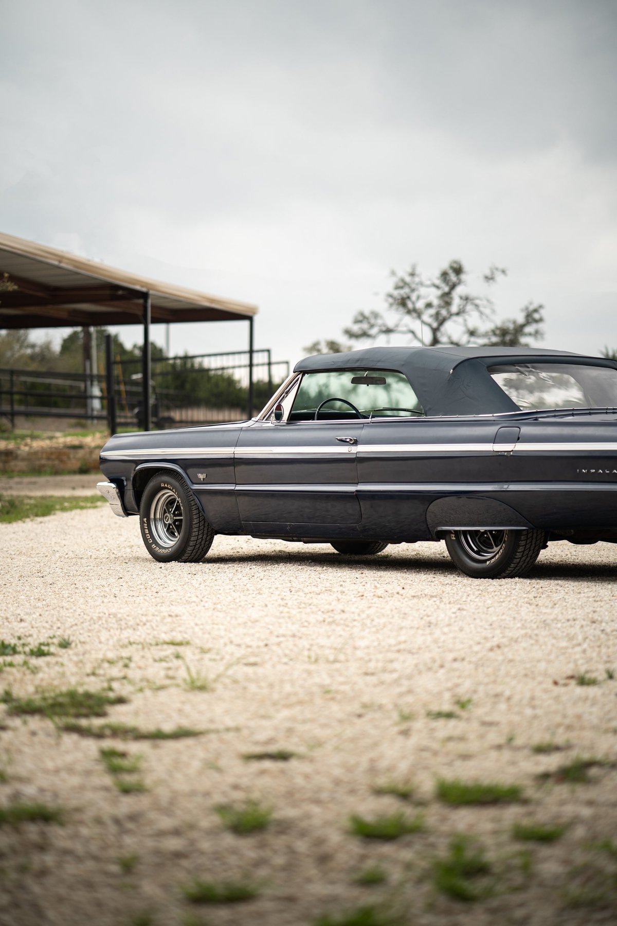 Dark blue 1964 Chevrolet Impala SS convertible with chrome trim and classic rims.