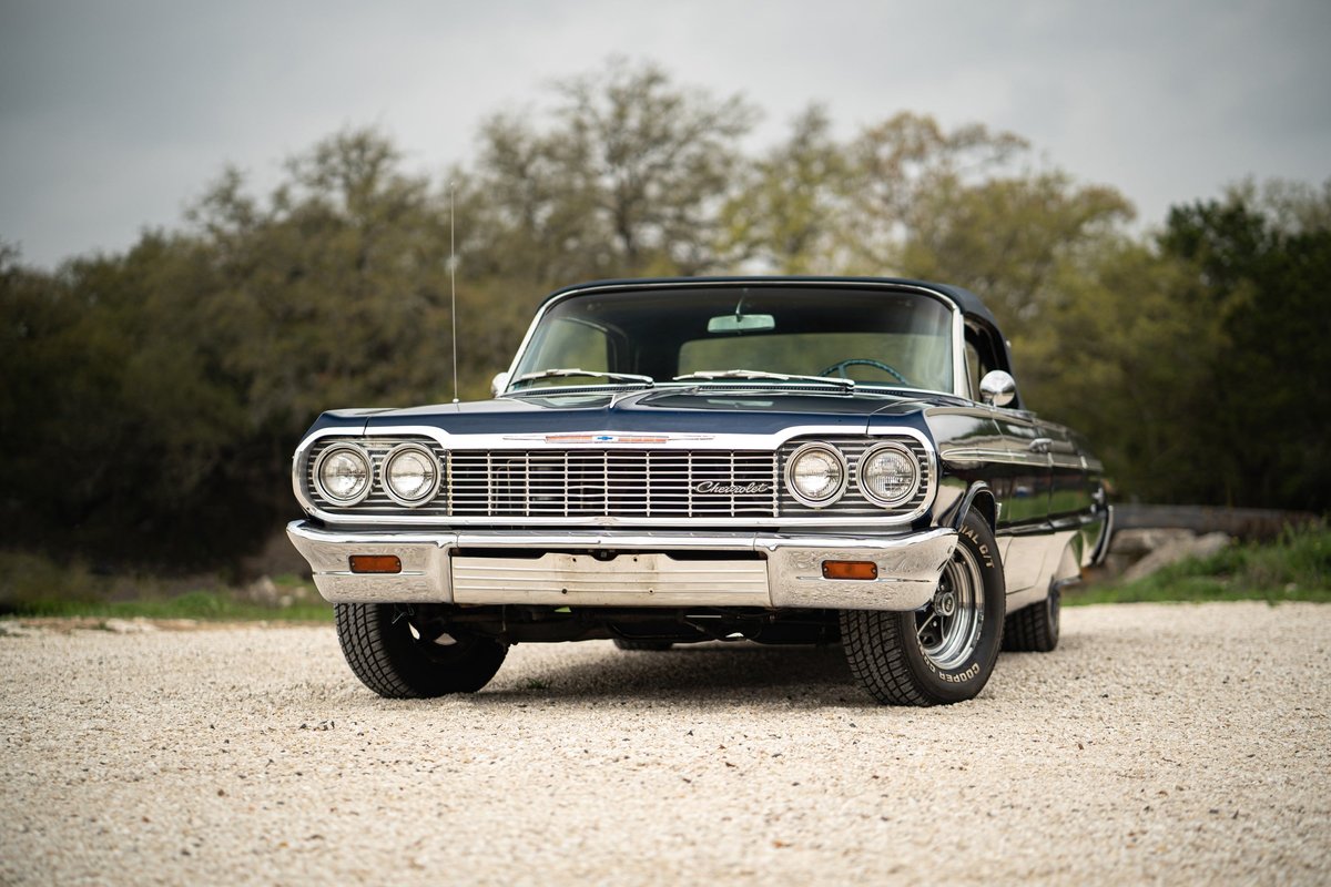 Front view of a dark blue 1964 Chevrolet Impala SS convertible with chrome trim and classic rims.