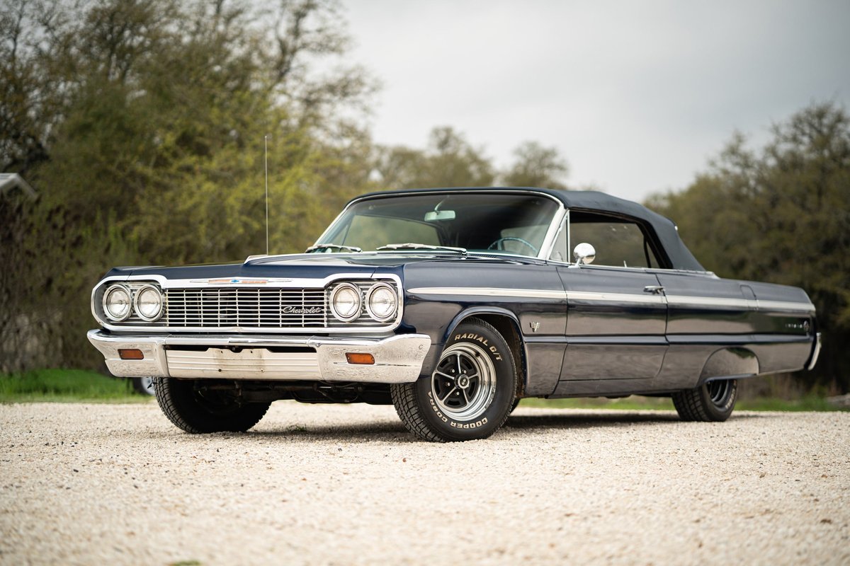 1964 Chevrolet Impala SS convertible in dark blue with chrome trim and classic rims.
