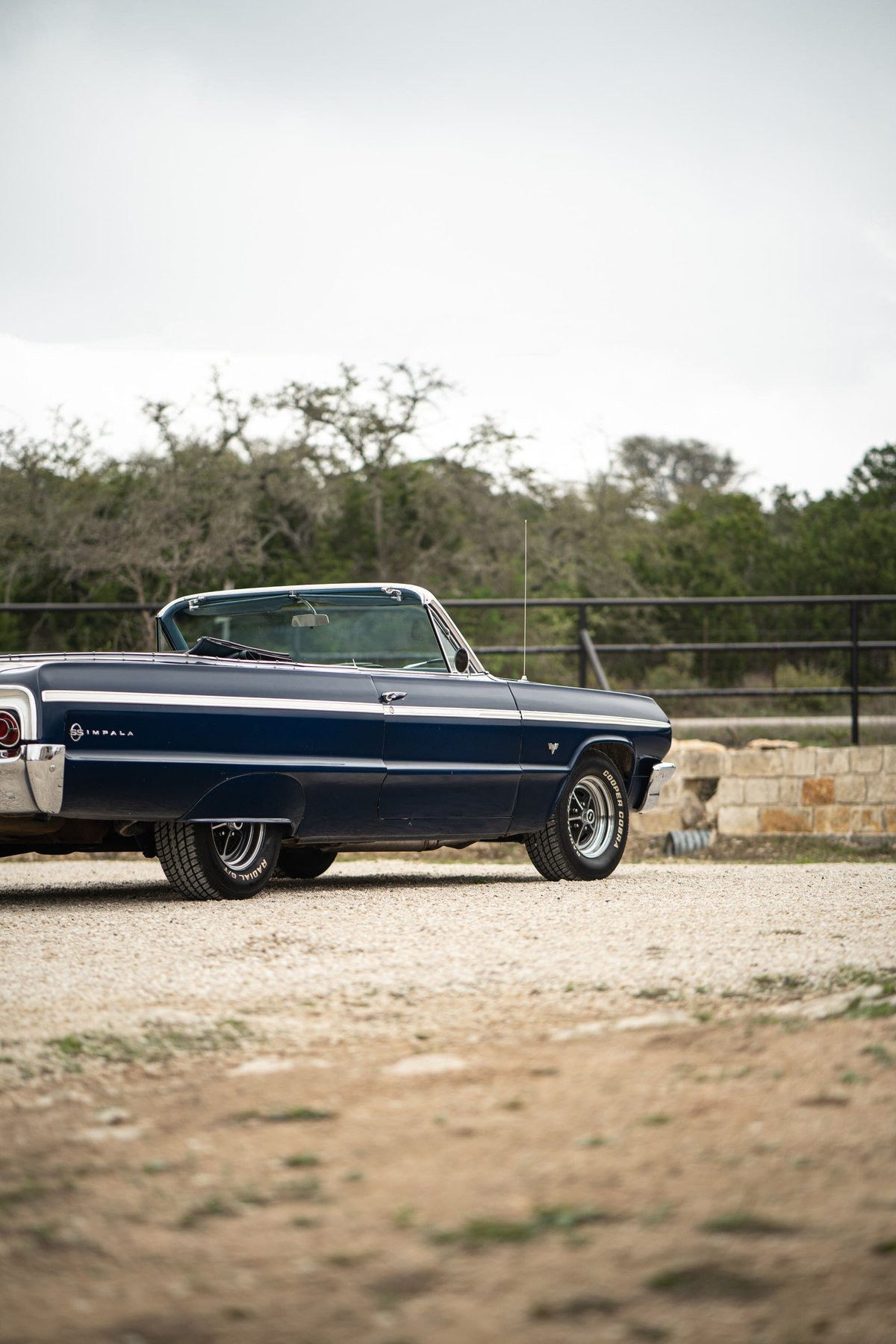 1964 Chevrolet Impala SS convertible, dark blue with chrome trim and vintage rims.