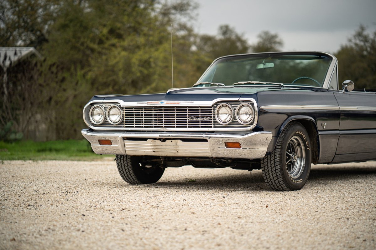 1964 dark blue Chevrolet Impala SS convertible with chrome trim and classic rims.