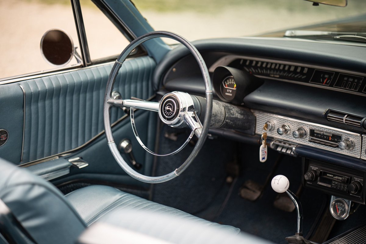 Interior of a 1964 Chevrolet Impala SS with blue vinyl trim and a chrome steering wheel.