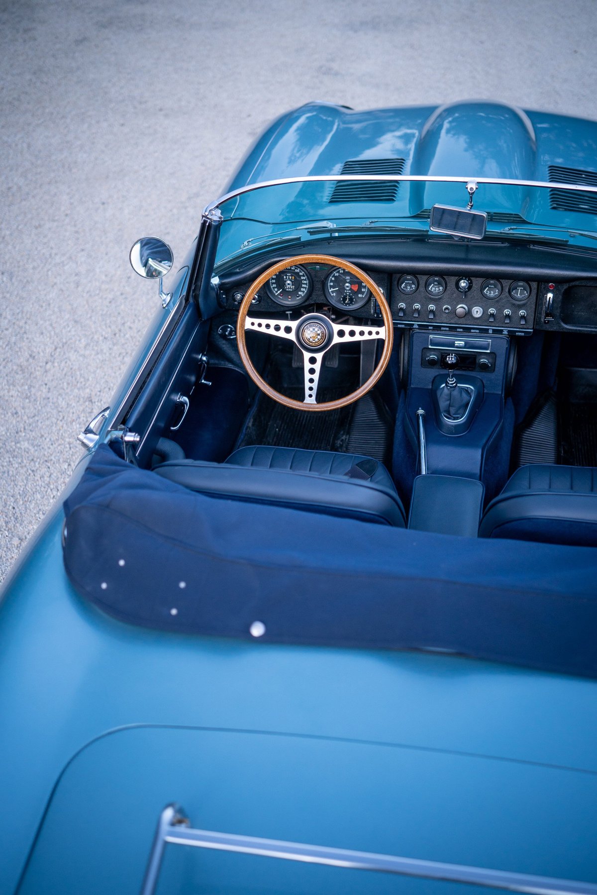 1966 Jaguar E-Type convertible interior in opalescent silver-blue. Features wood-rimmed steering wheel.