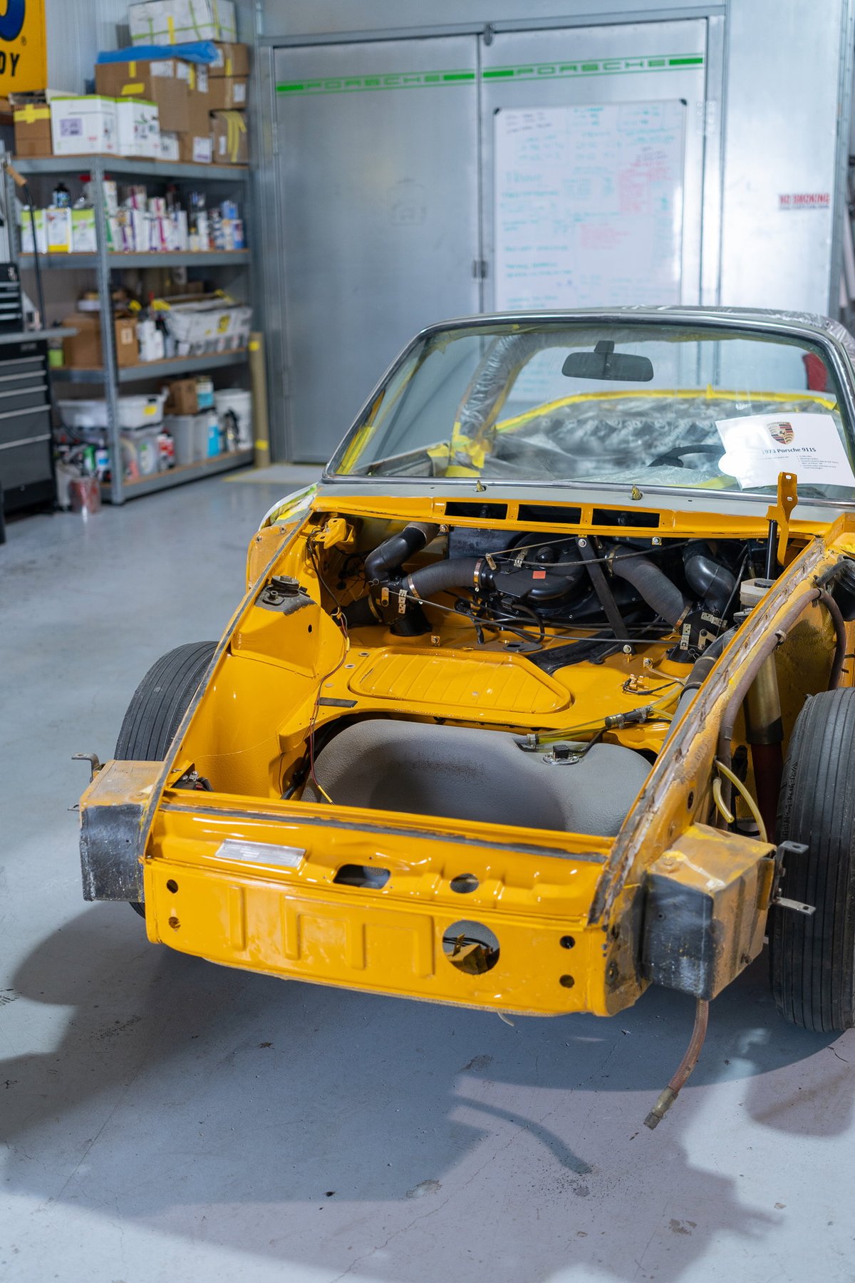 Yellow Porsche 911 track car stripped down for racing, with exposed engine bay and minimal trim.