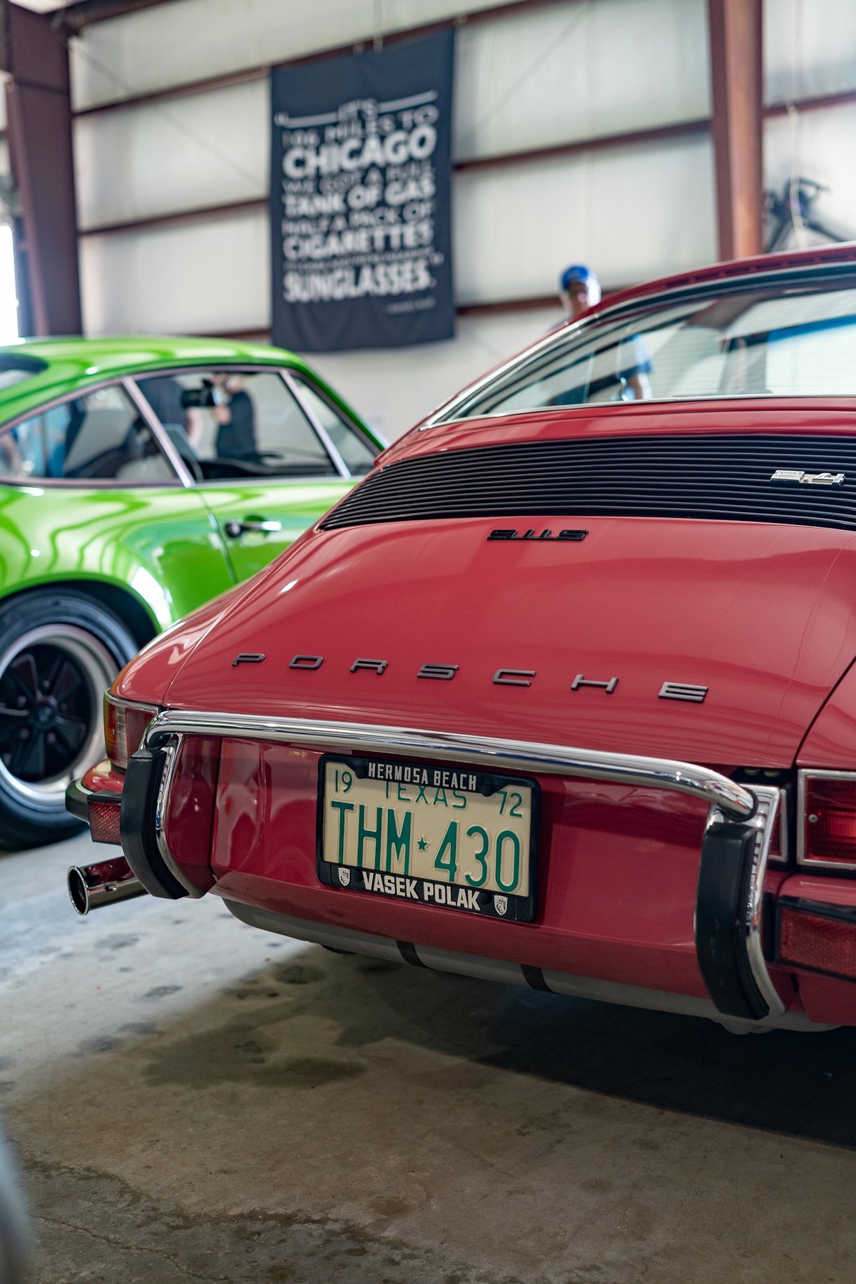Rear view of a red 1972 Porsche 911 Targa with chrome trim and Vasek Polak plates.
