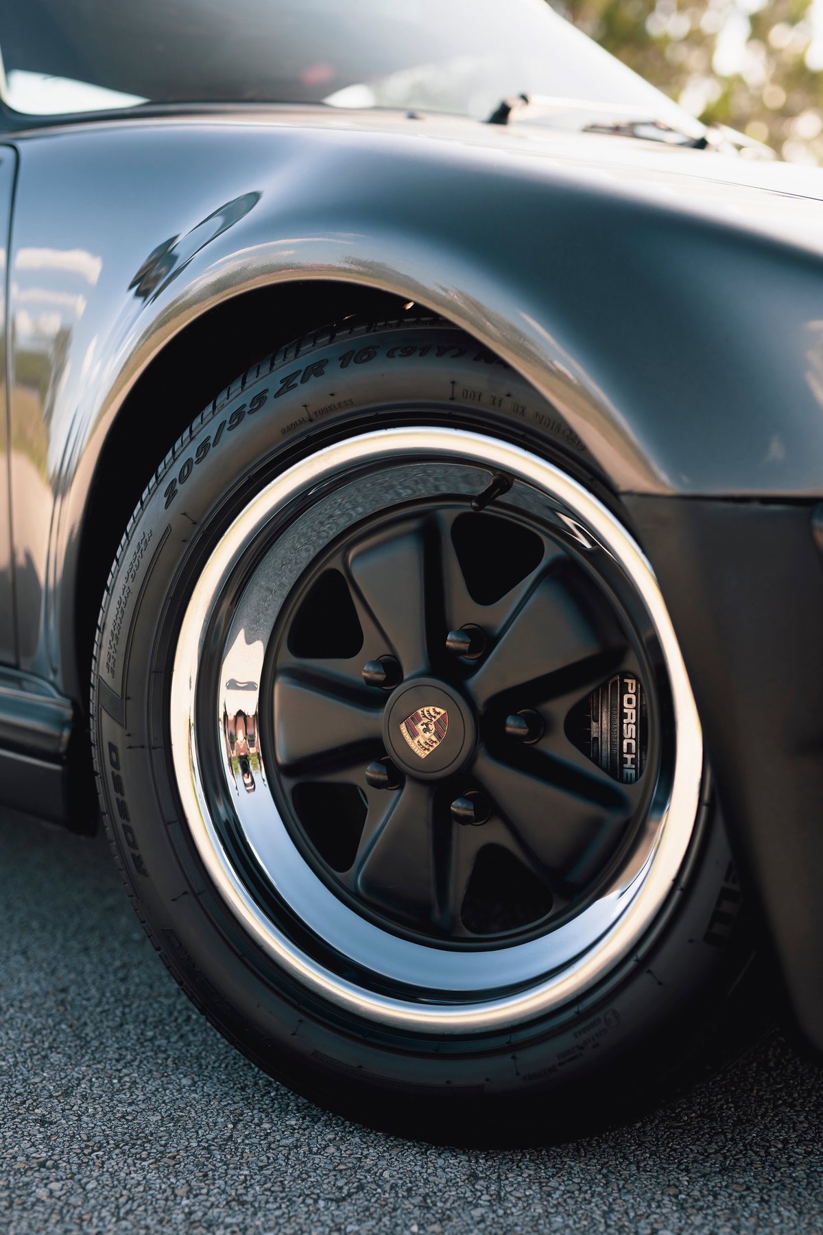 Close-up of a black 1989 Porsche 930 Turbo Flachbau wheel with polished lip and Porsche brake caliper.