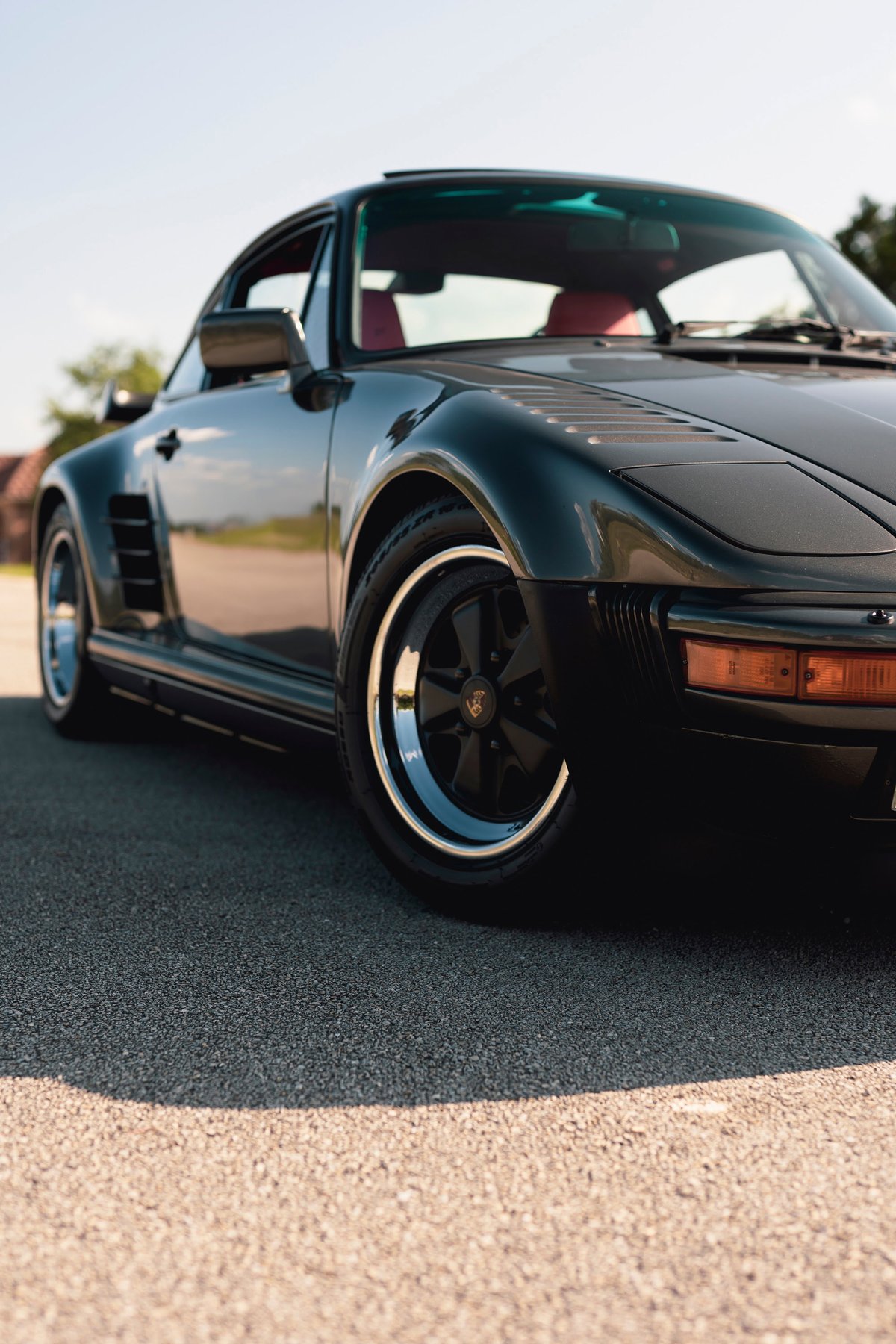 1989 Porsche 930 Turbo Flachbau in black, featuring Fuchs rims with polished lips.