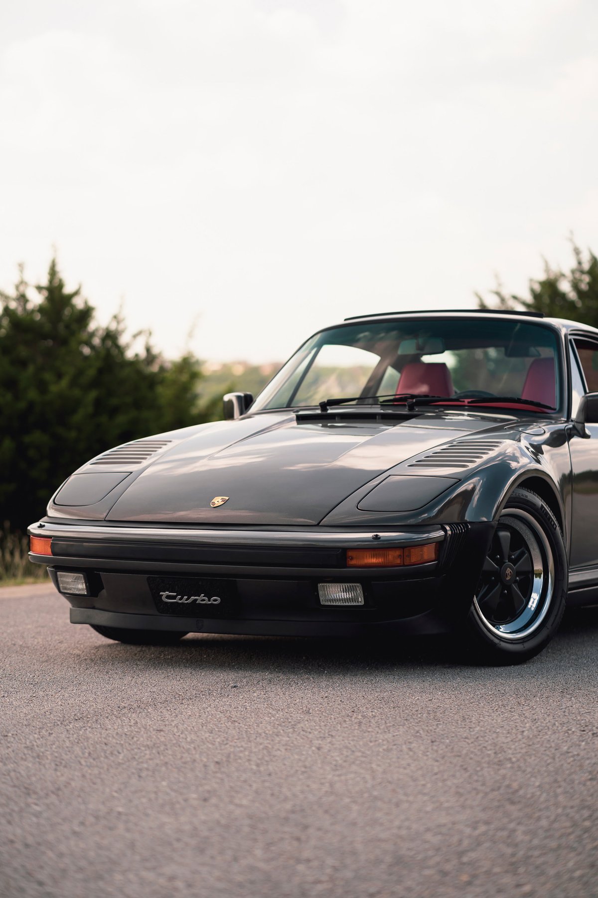 1989 Porsche 930 Turbo Flachbau with red interior and black Fuchs rims.