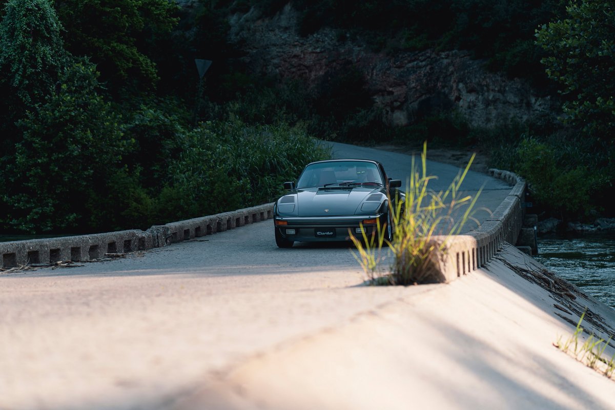 Black 1989 Porsche 930 Turbo Flachbau on a bridge.