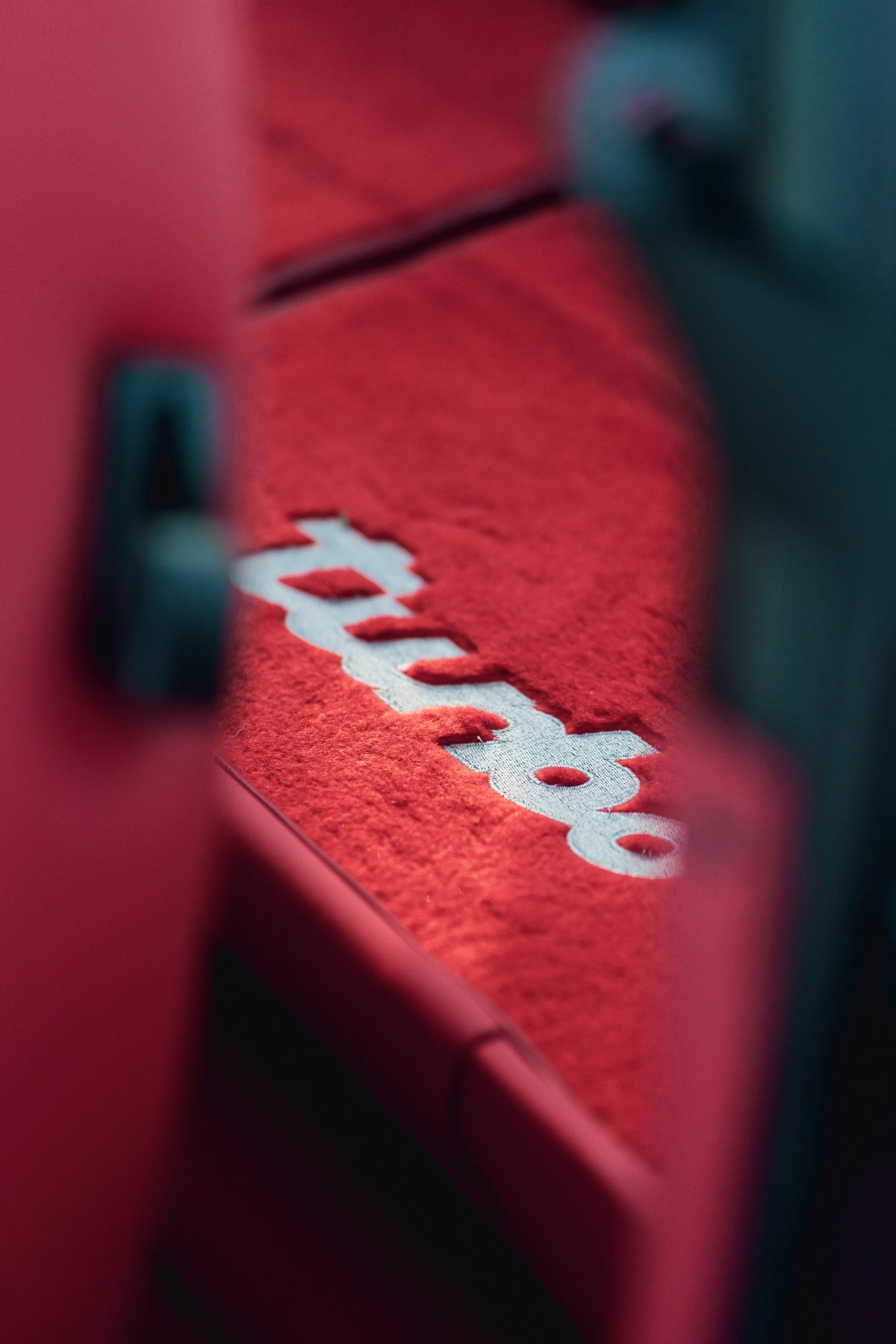 Red 1989 Porsche 930 Turbo Flachbau floor mat with white "Turbo" lettering.