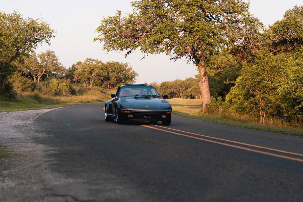 Black 1989 Porsche 930 Turbo Flachbau on a winding road.