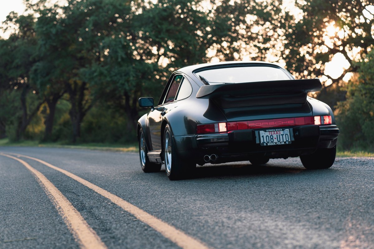 Rear view of a black 1989 Porsche 930 Turbo Flachbau with its signature whale tail spoiler.
