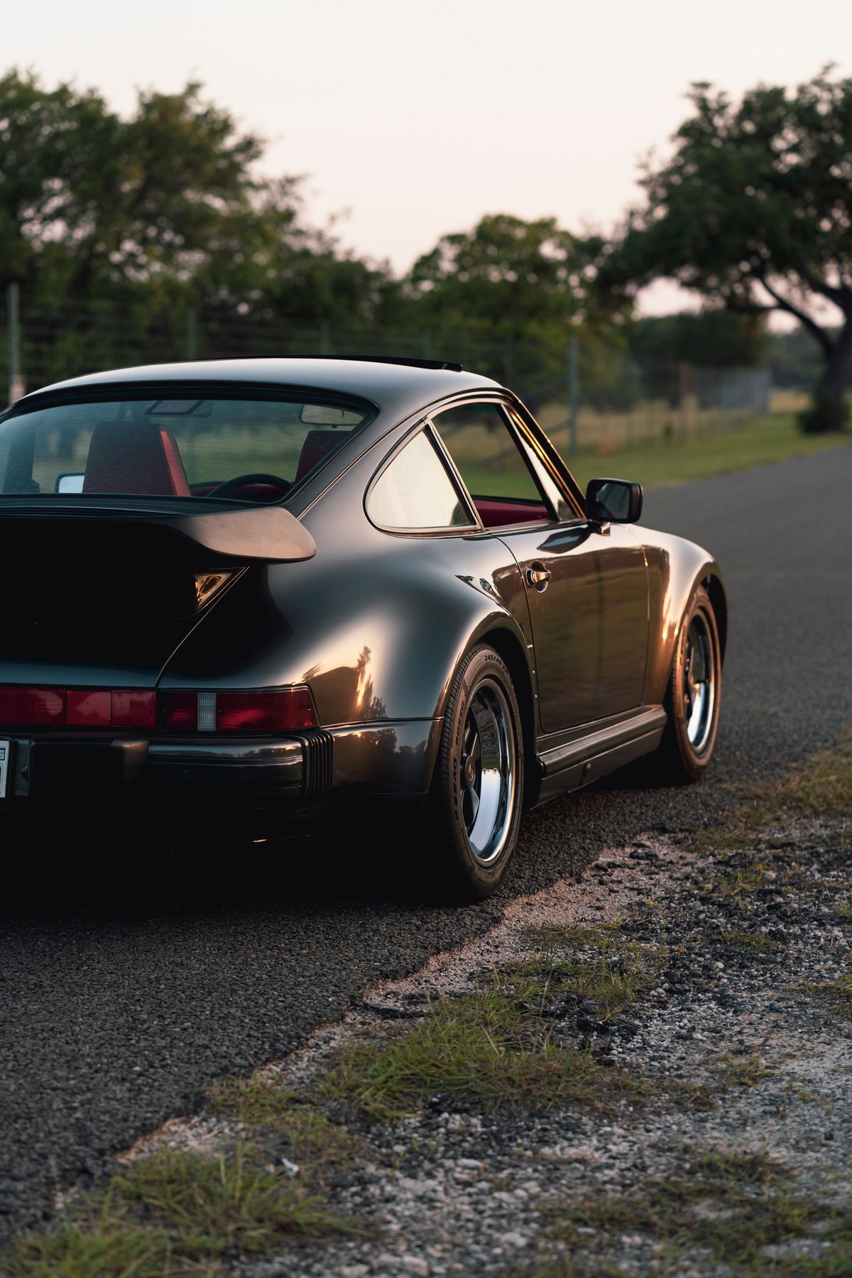 Black 1989 Porsche 930 Turbo Flachbau coupe with red interior and Fuchs wheels.