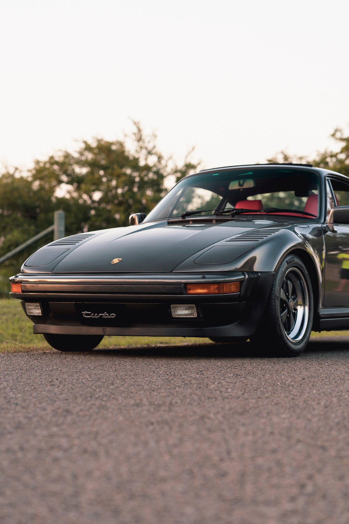 1989 Porsche 930 Turbo Flachbau with red interior, black exterior and chrome-lipped rims.