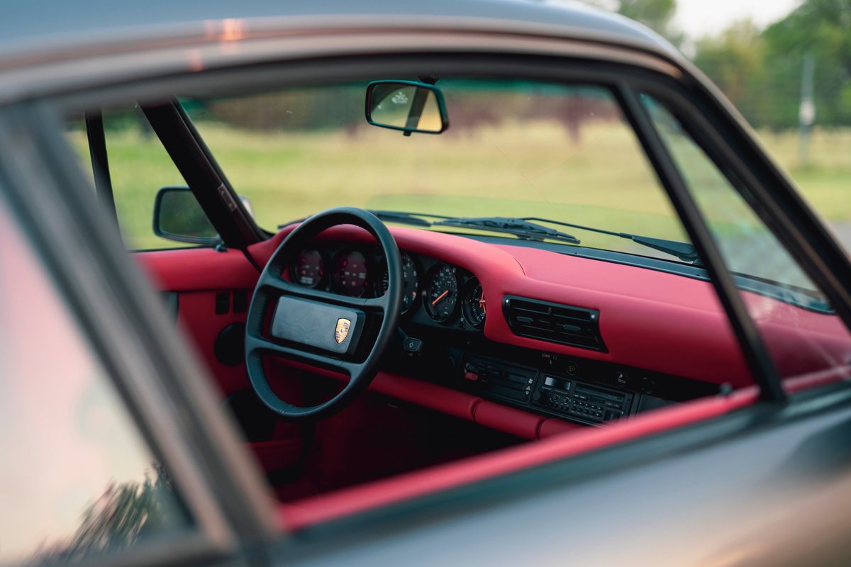 Interior of a 1989 Porsche 930 Turbo Flachbau, featuring a red dashboard and seats.