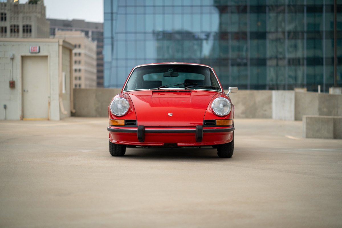 Front view of a Bahia Red 1973 Porsche 911S with chrome trim and black bumperettes.