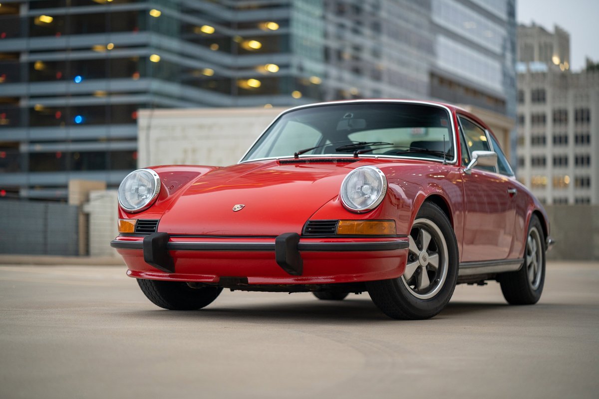 A red 1973 Porsche 911S coupe with chrome trim and Fuchs rims.