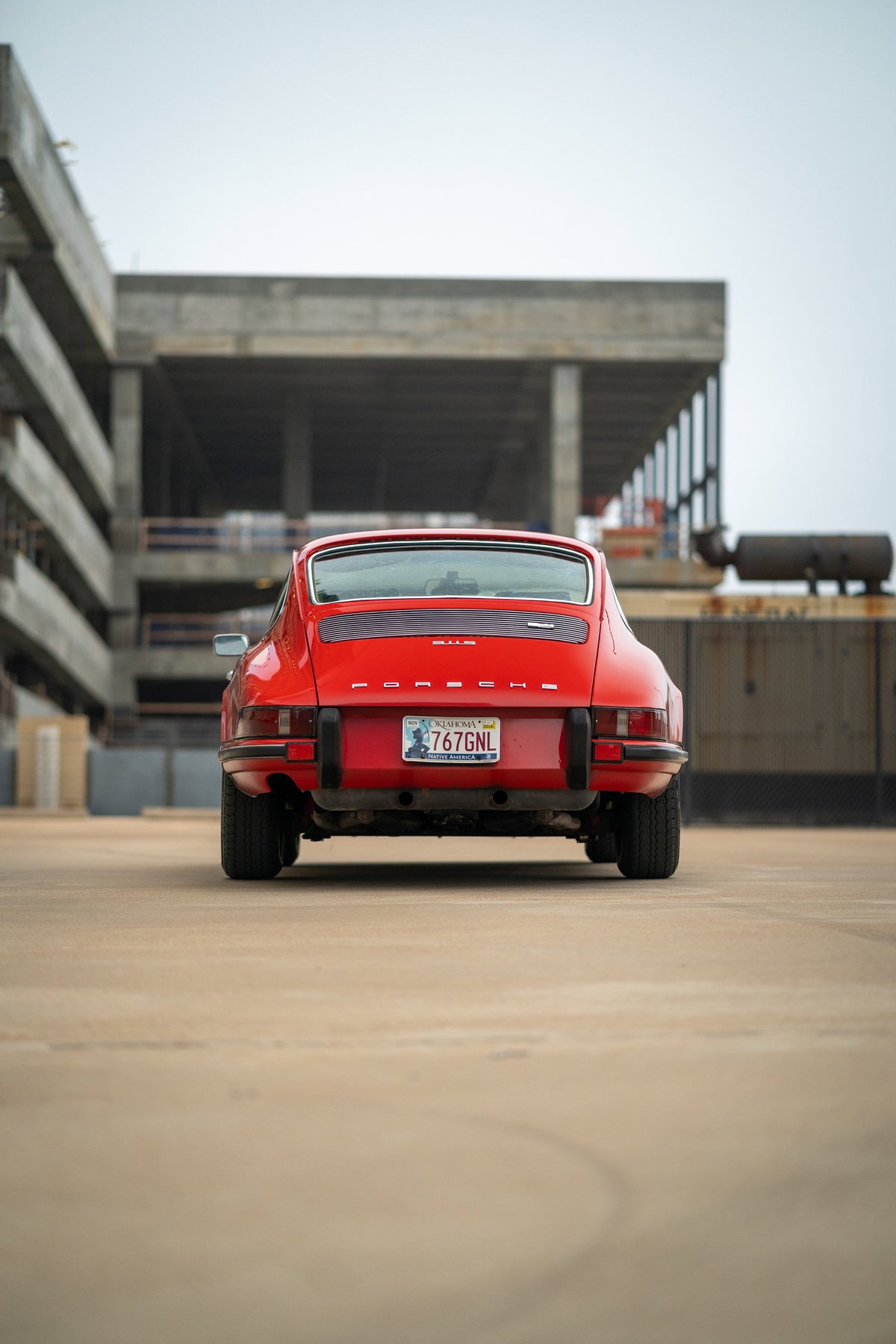 Rear view of a red 1973 Porsche 911S with chrome trim and gold California plates.