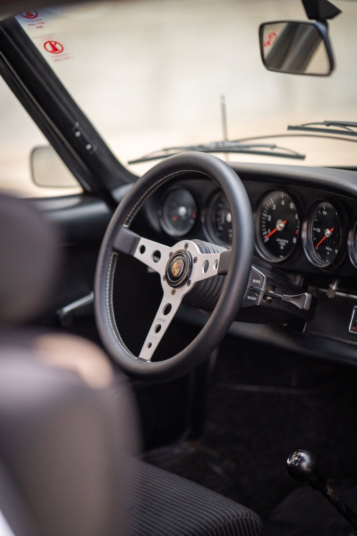 Close-up of the steering wheel and dashboard of a 1973 Porsche 911S in Bahia Red.