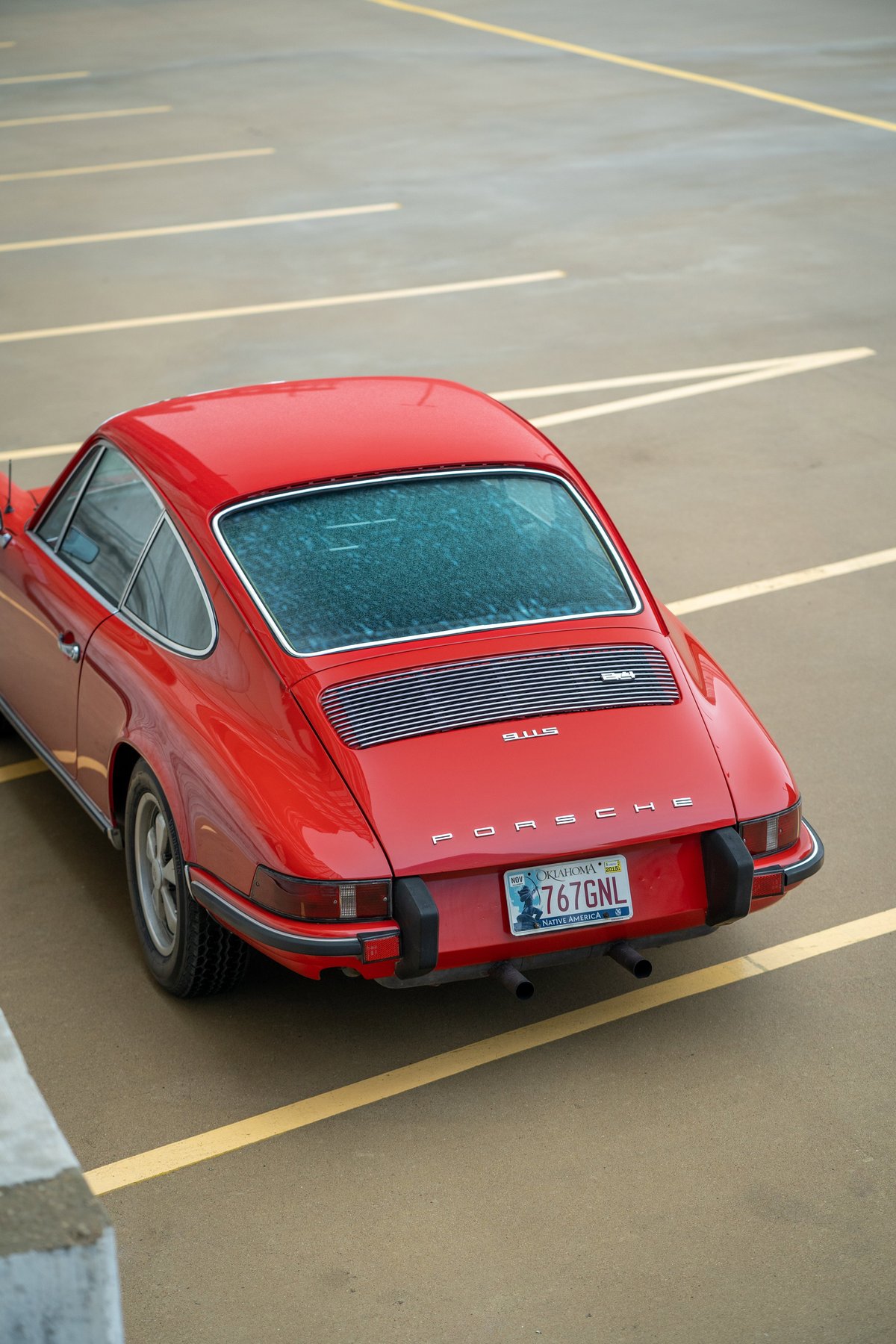 Red 1973 Porsche 911S with chrome trim and dual exhaust pipes.