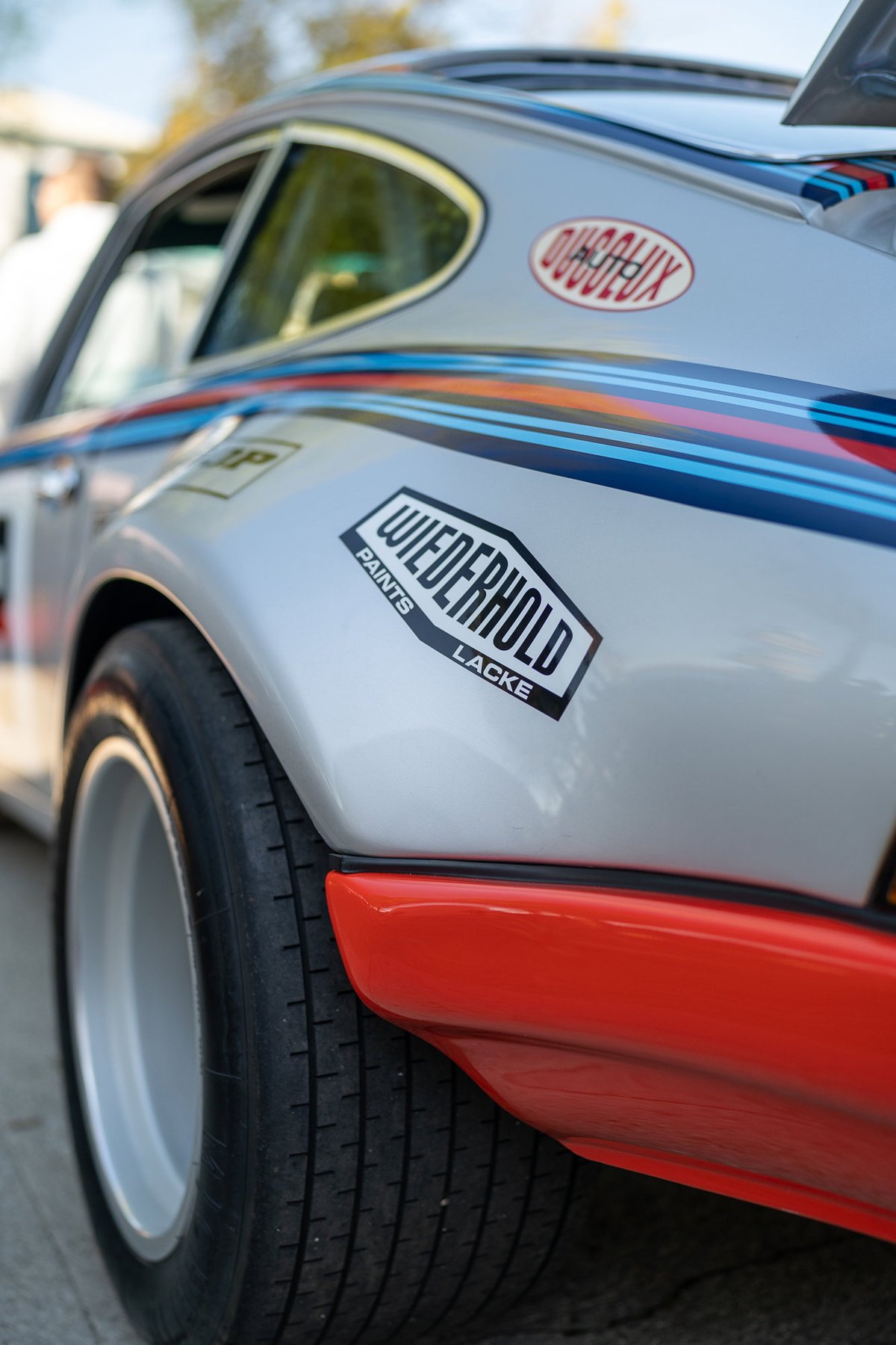 Porsche 911 silver livery with racing decals and orange trim.