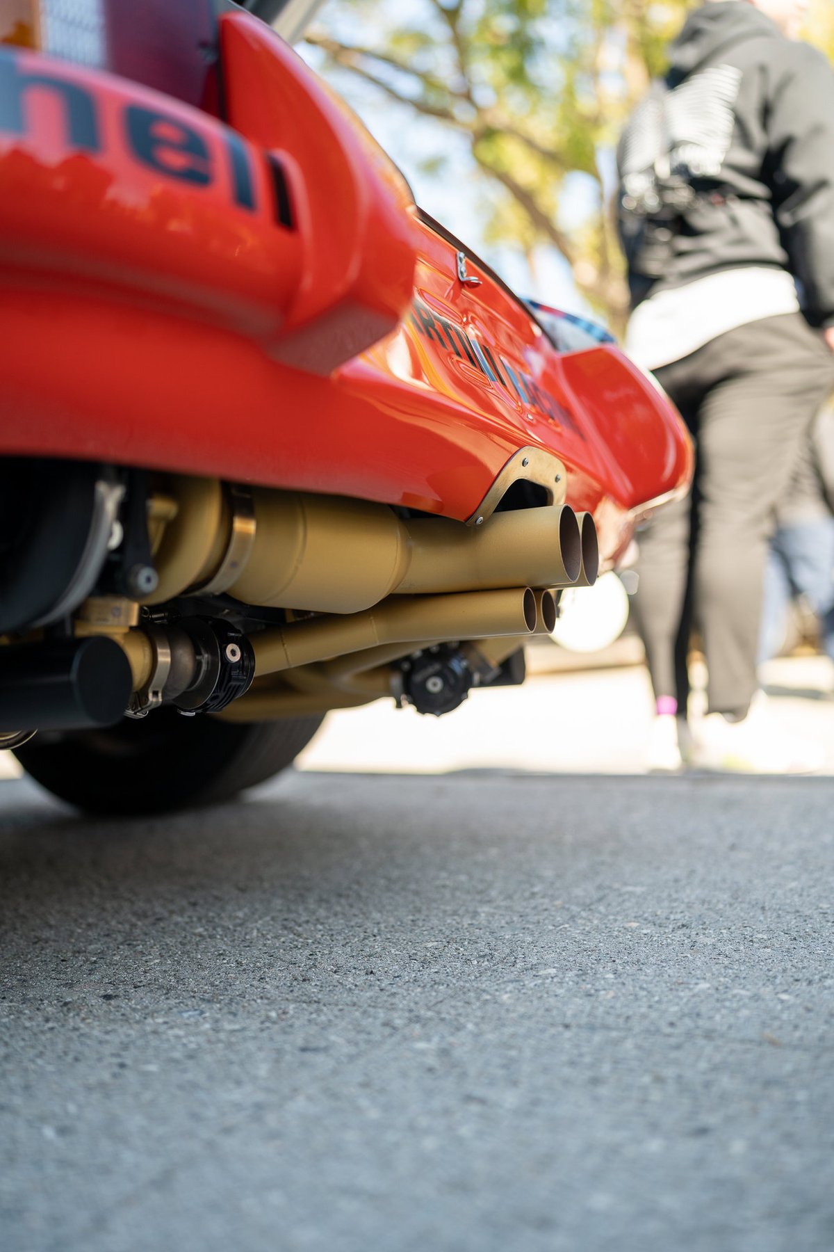 Close-up of a red Porsche 911's dual exhaust system and livery.