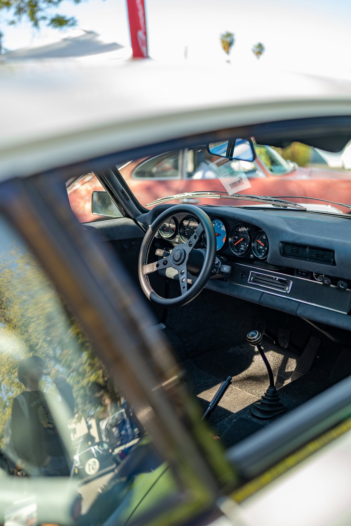 Interior of a vintage Porsche 911 with aftermarket steering wheel and shifter.