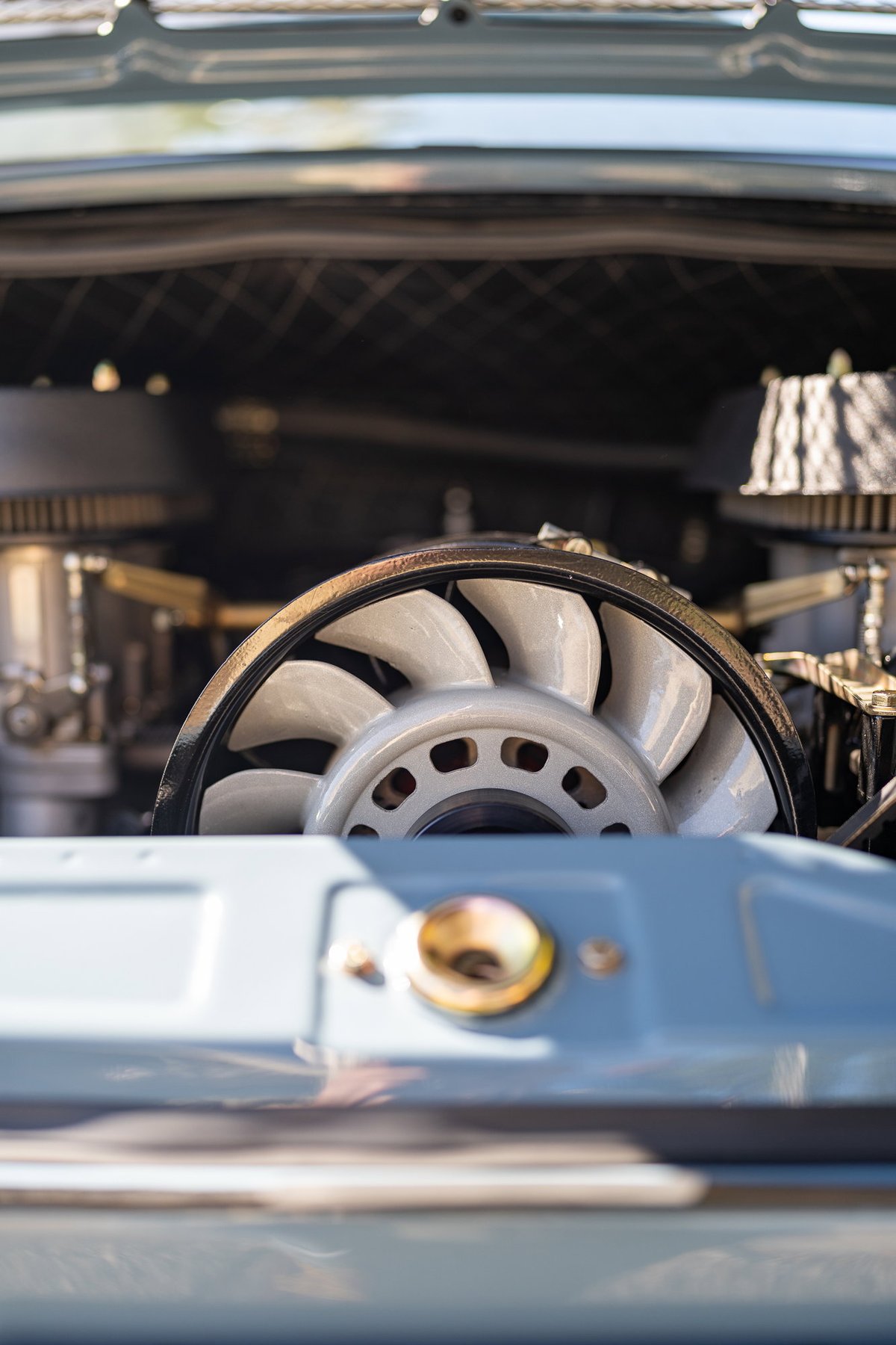 Close-up of a classic Porsche 911's engine cooling fan with twin carburetors.