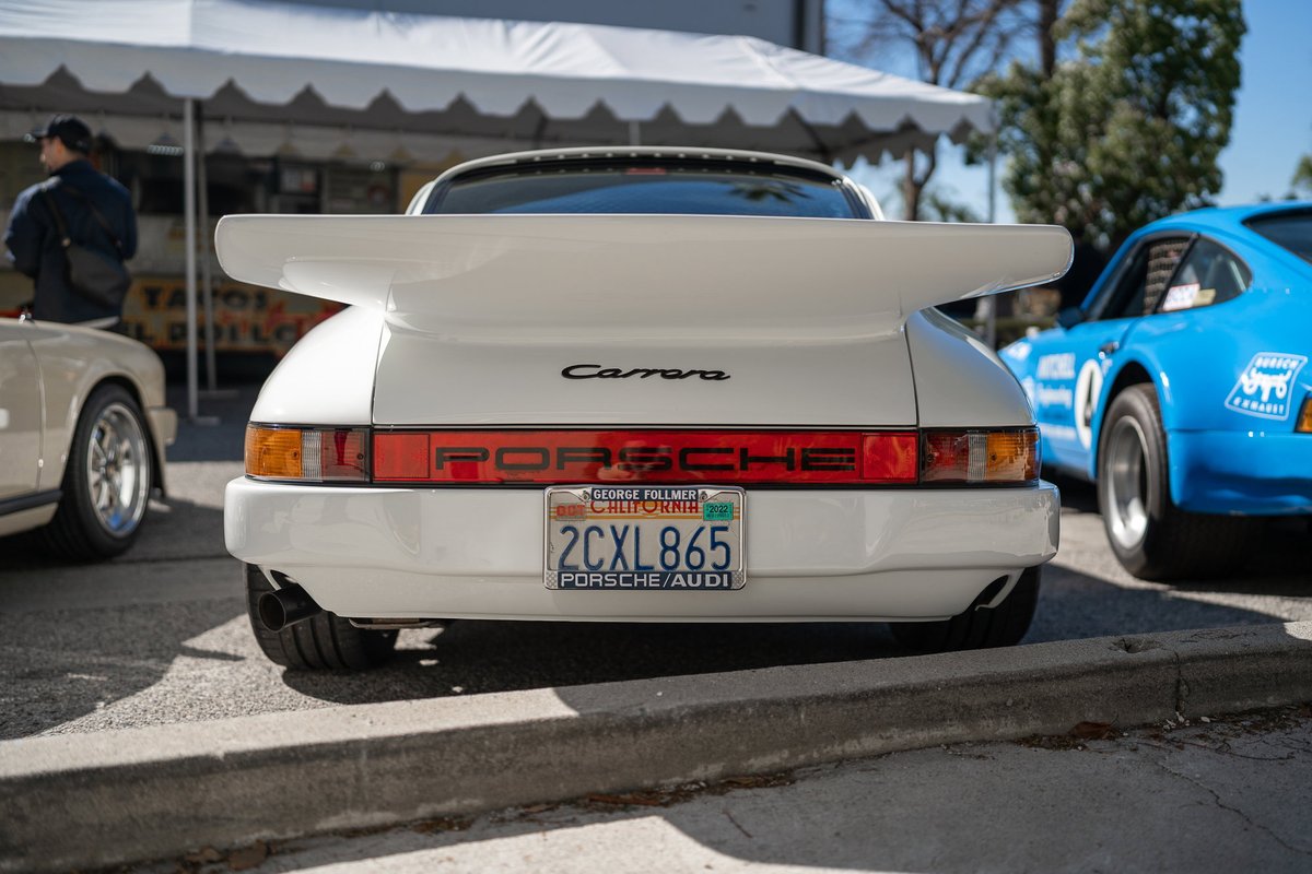 White Porsche 911 Carrera with large wing and "PORSCHE" script taillights.
