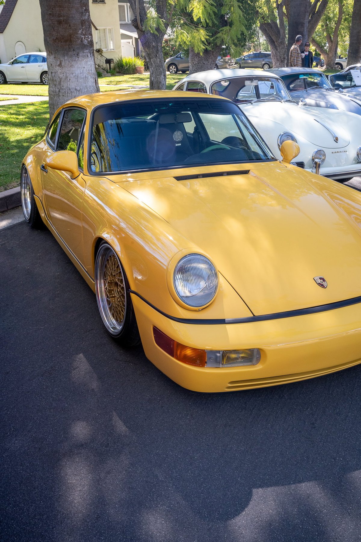 Yellow Porsche 911 (964) Carrera 2 with gold mesh rims and widebody trim.