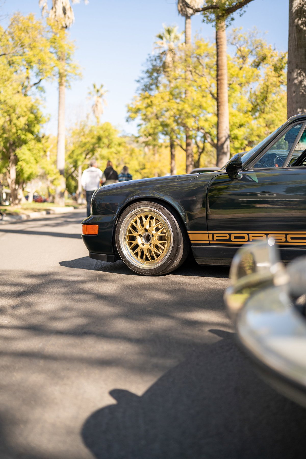 Black Porsche 911 with gold BBS rims and stripe livery.