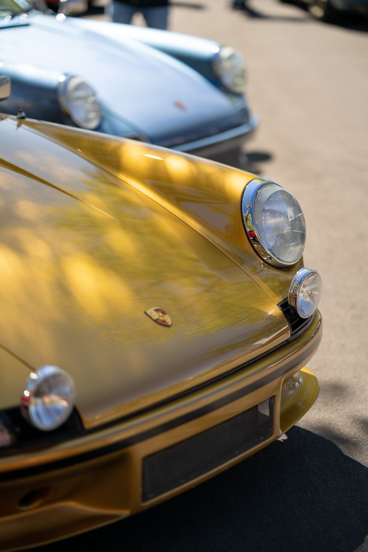 Close-up of a metallic gold 1974 Porsche 911 Carrera Targa front bumper and headlight.
